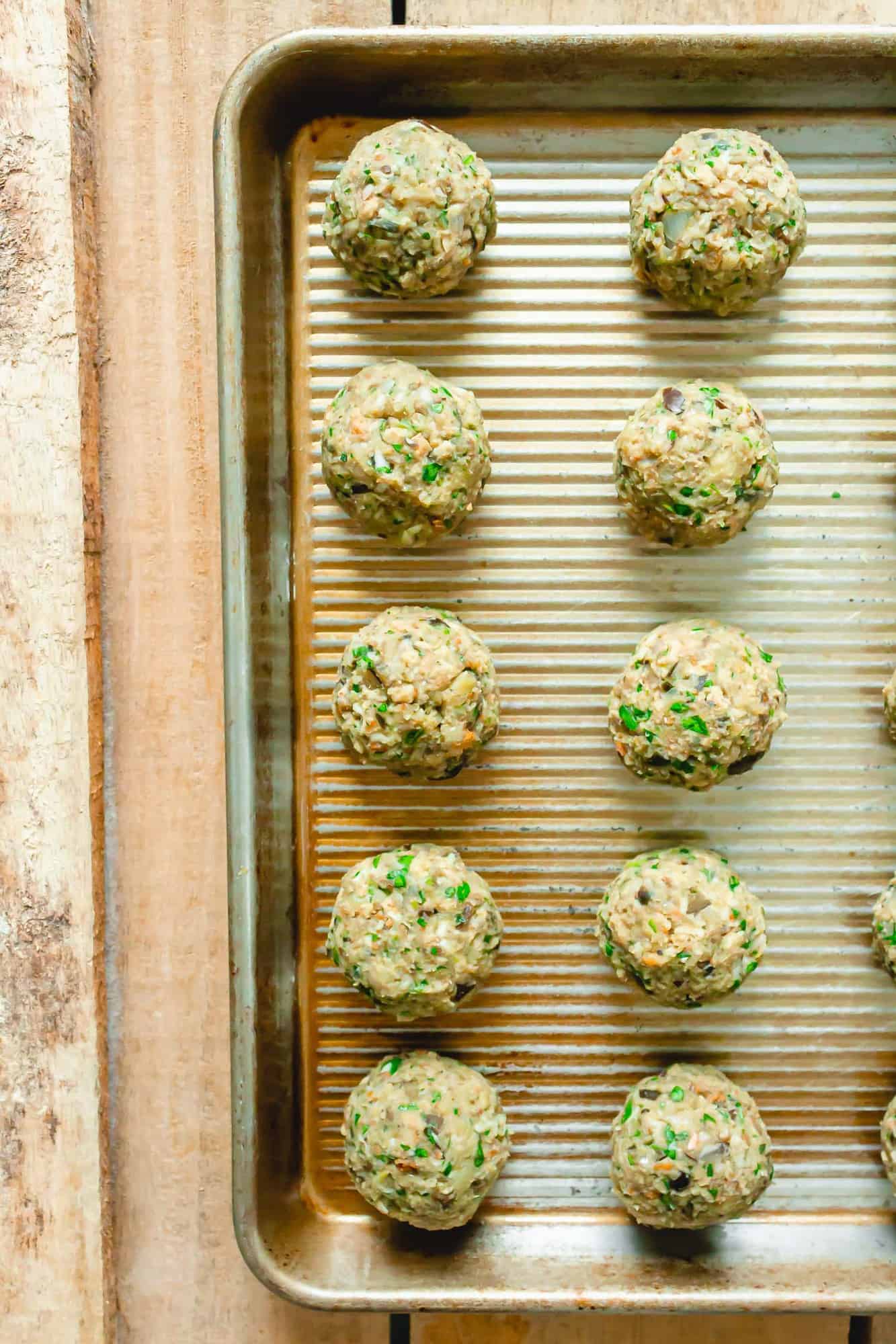 Uncooked vegetarian meatballs on a baking sheet.