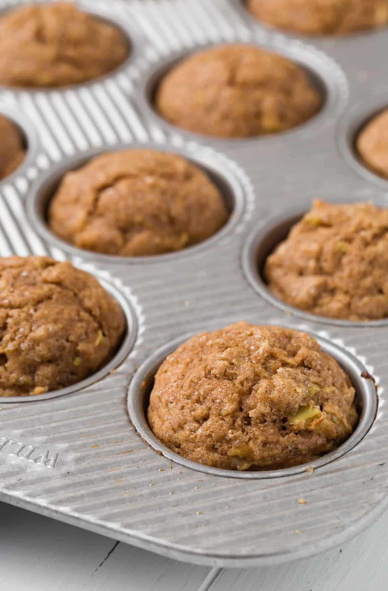 Apple muffins made with whole wheat flour in a silver muffin pan.