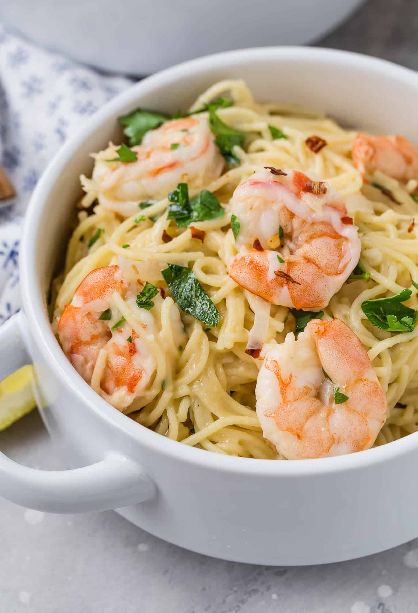 Shrimp scampi pasta in a white two-handled bowl.