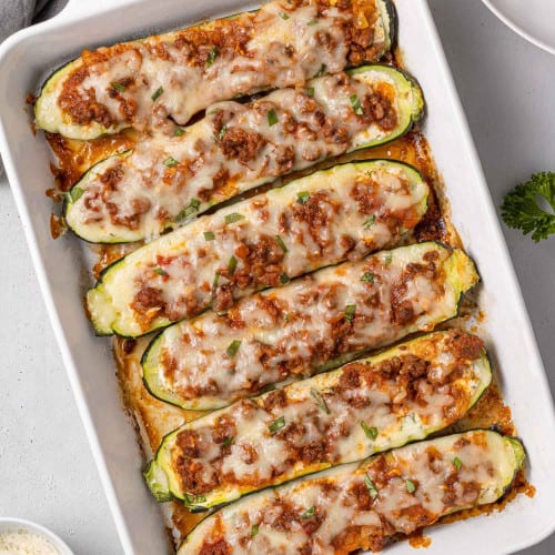 Lasagna boats in a white baking dish, filled with ricotta and meat sauce.
