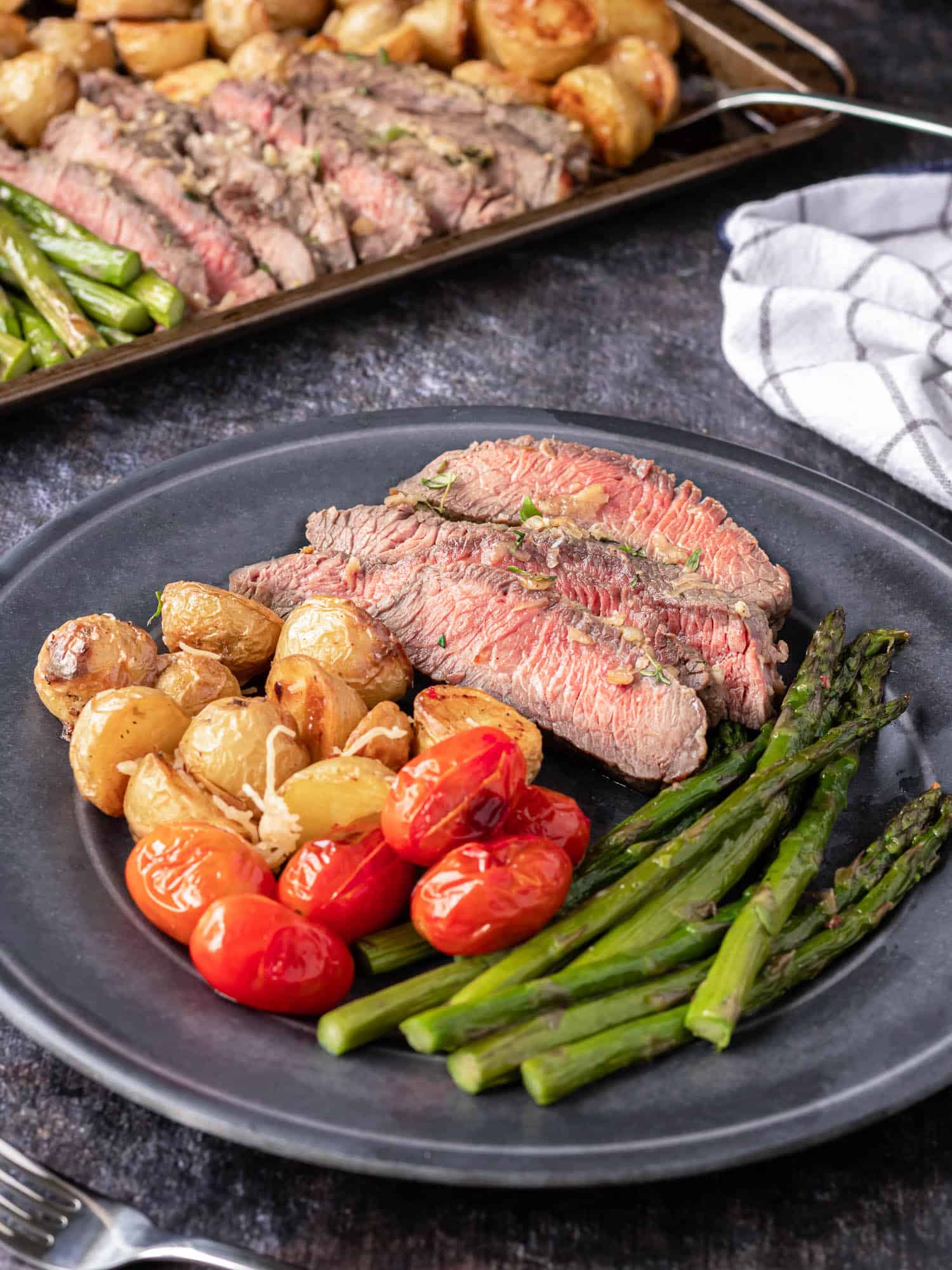 Plated steak dinner with tomatoes, asparagus, and tomatoes.