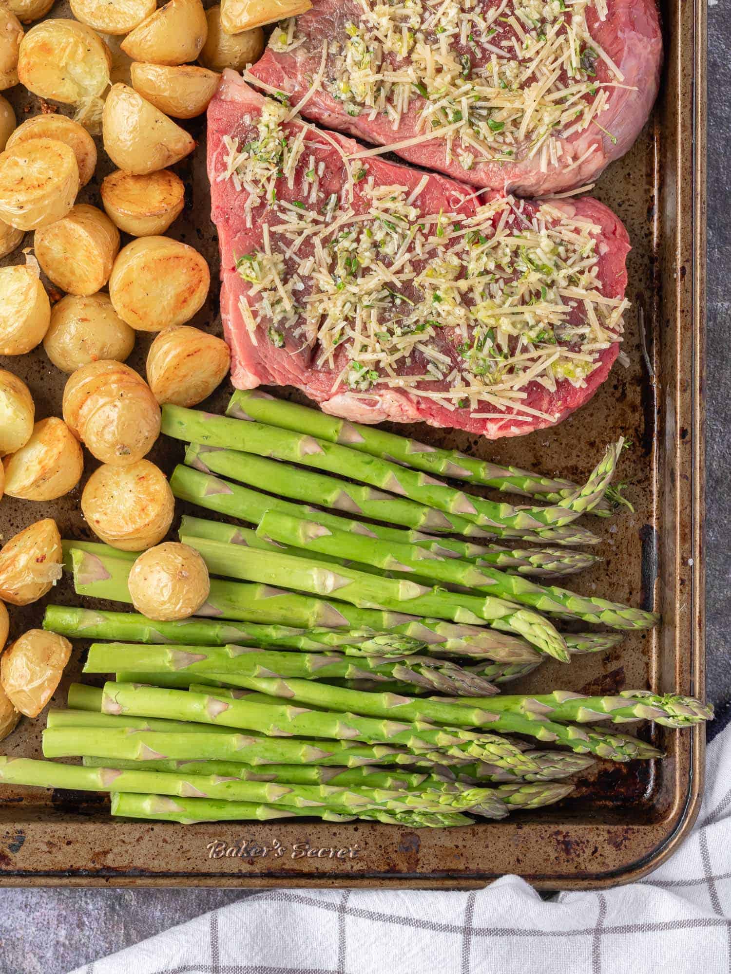 Uncooked steak and vegetables on a sheet pan.