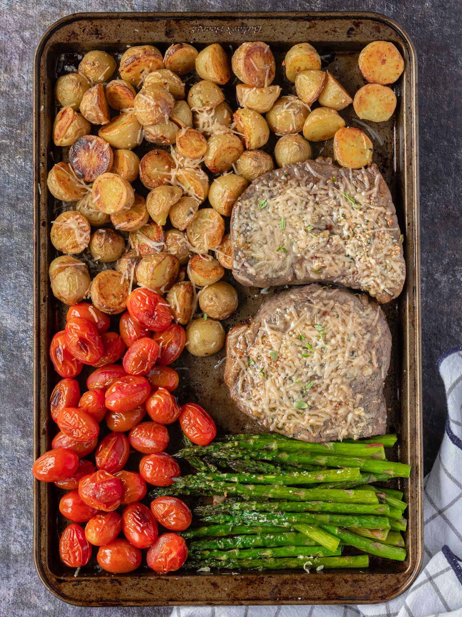 Cooked steak and vegetables on a large sheet pan.