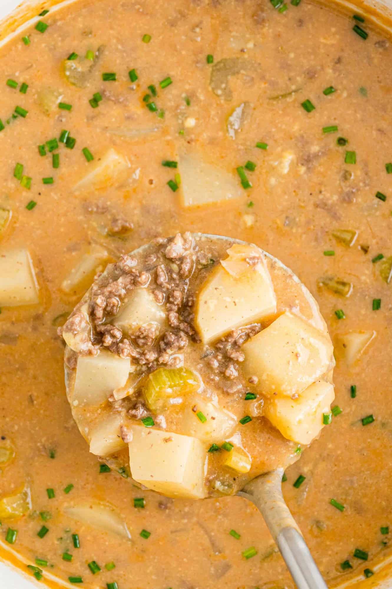 Chunky beef and potato soup in a ladle.