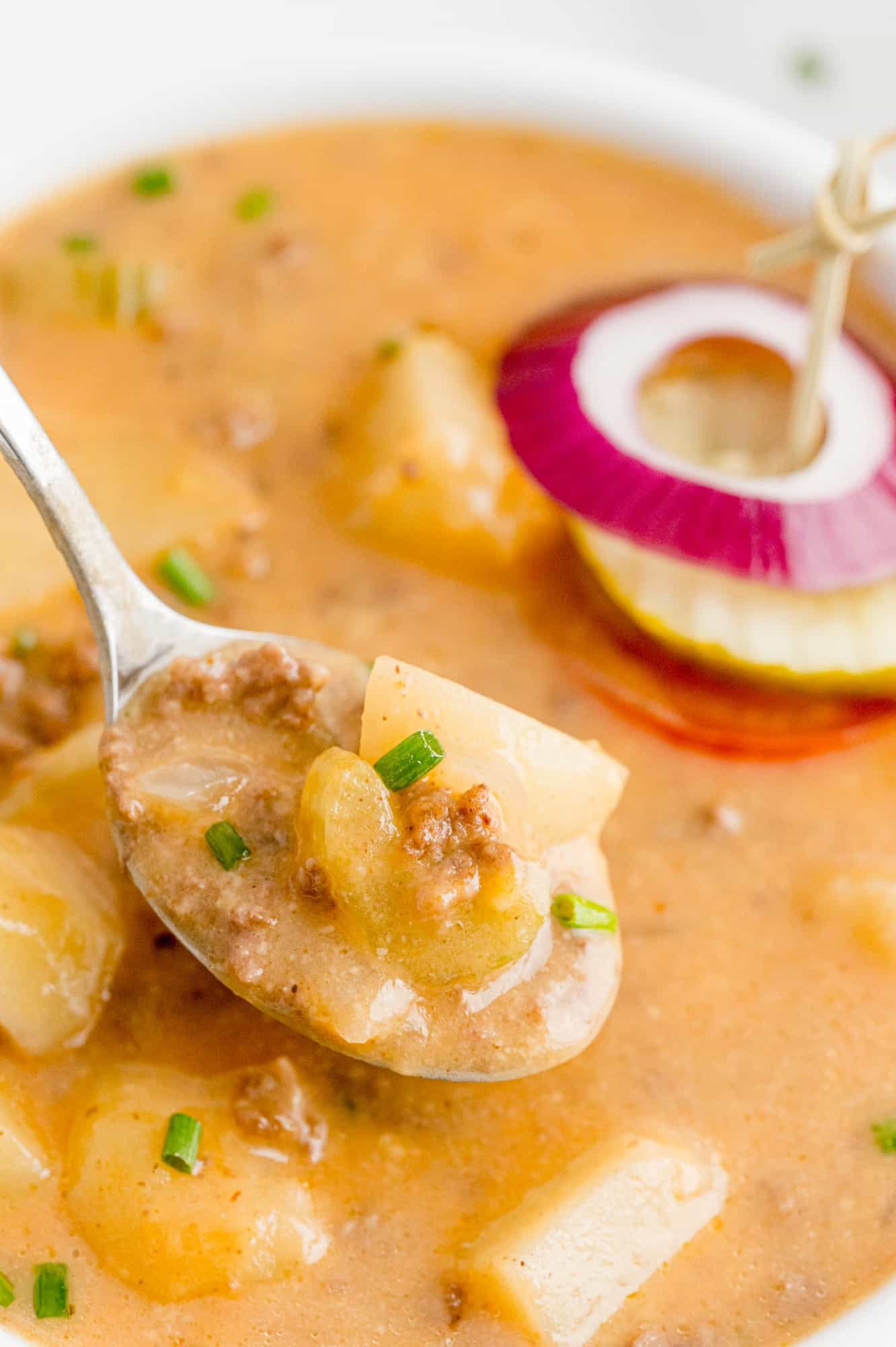 Soup on a spoon above a bowl of soup.