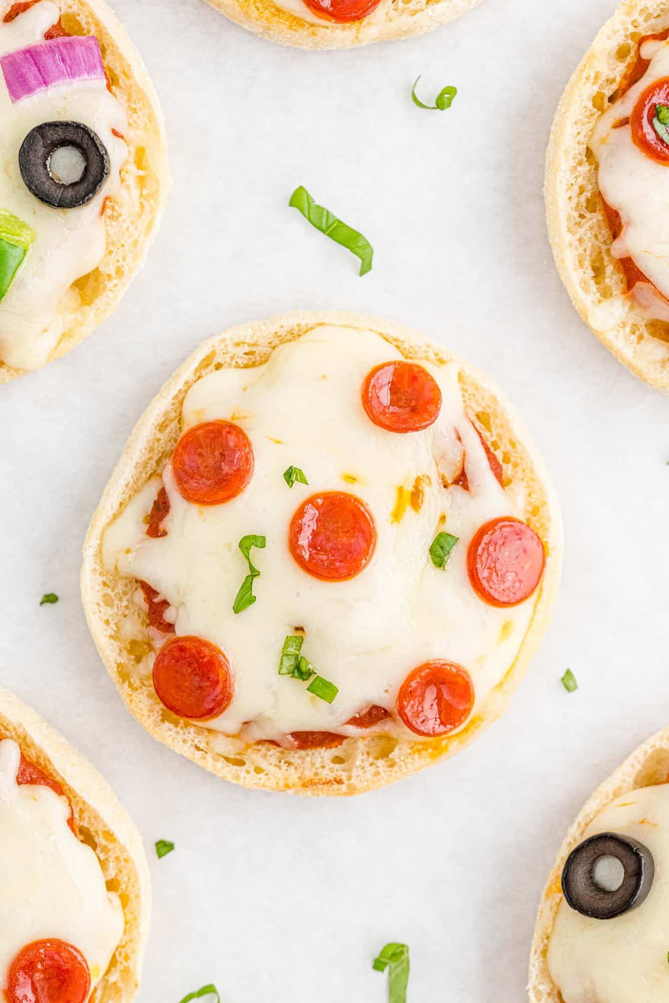 Overhead view of a pepperoni english muffin pizza, others partially visible.