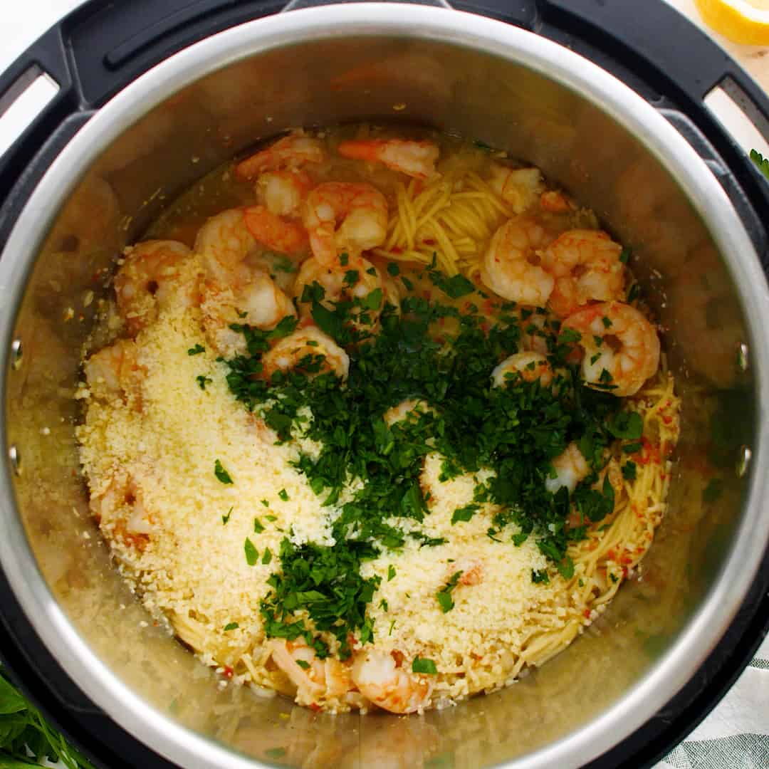 Parsley and cheese on top of cooked shrimp and pasta.