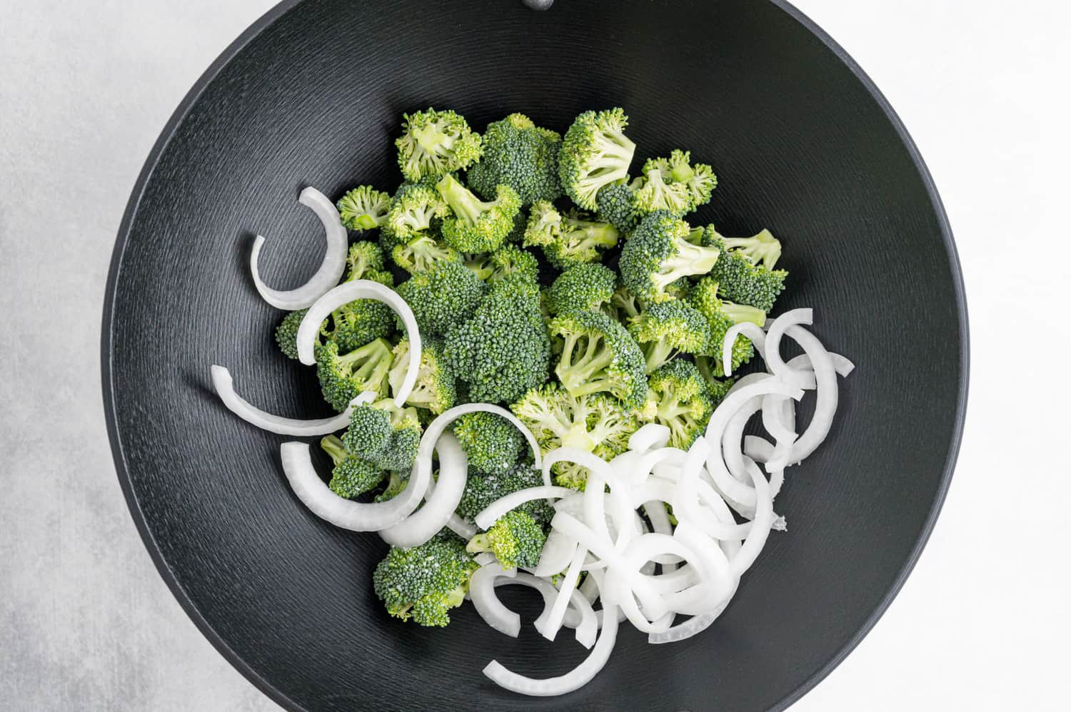 Broccoli and onion in a black wok.