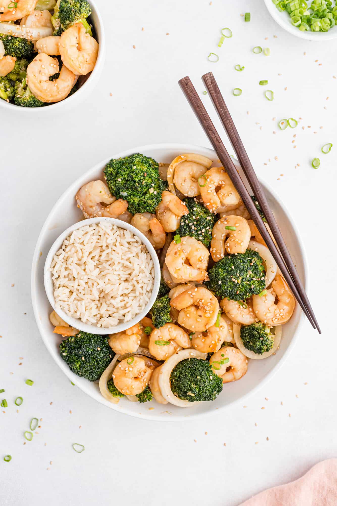Broccoli and shrimp stir fry in a bowl with rice and chopsticks.