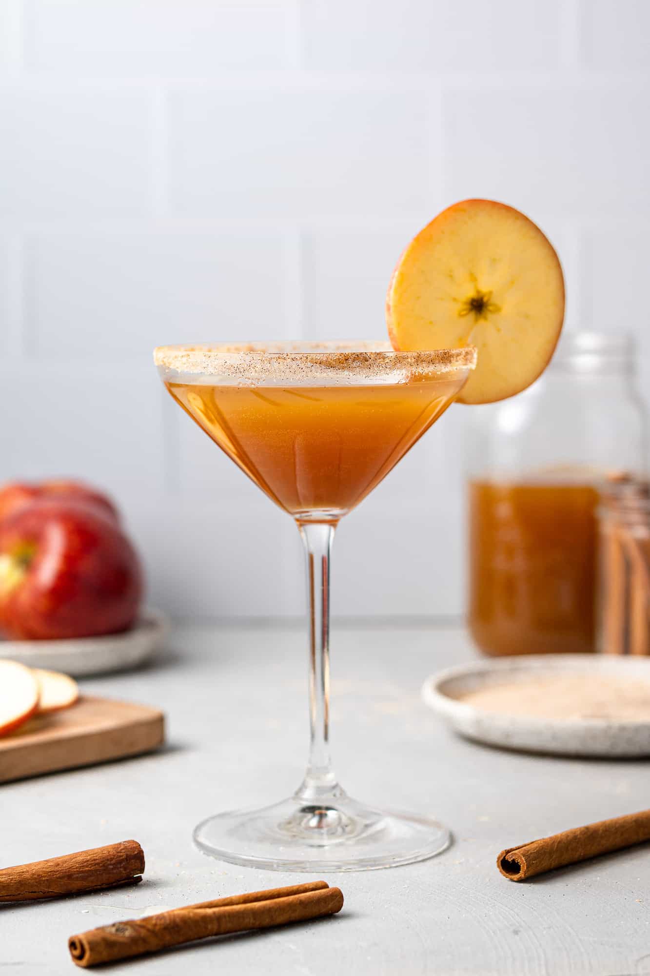 An apple cider based cocktail in a martini glass against a white background.