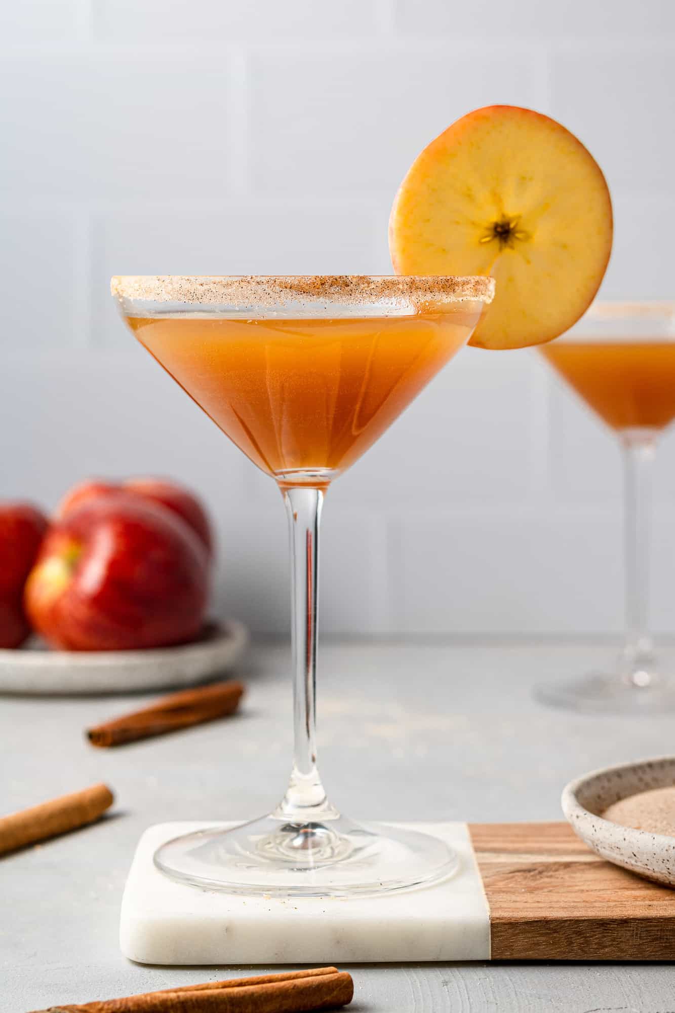 Martini glass filled with apple cider and simple syrup, garnished with cinnamon sugar and an apple slice. 