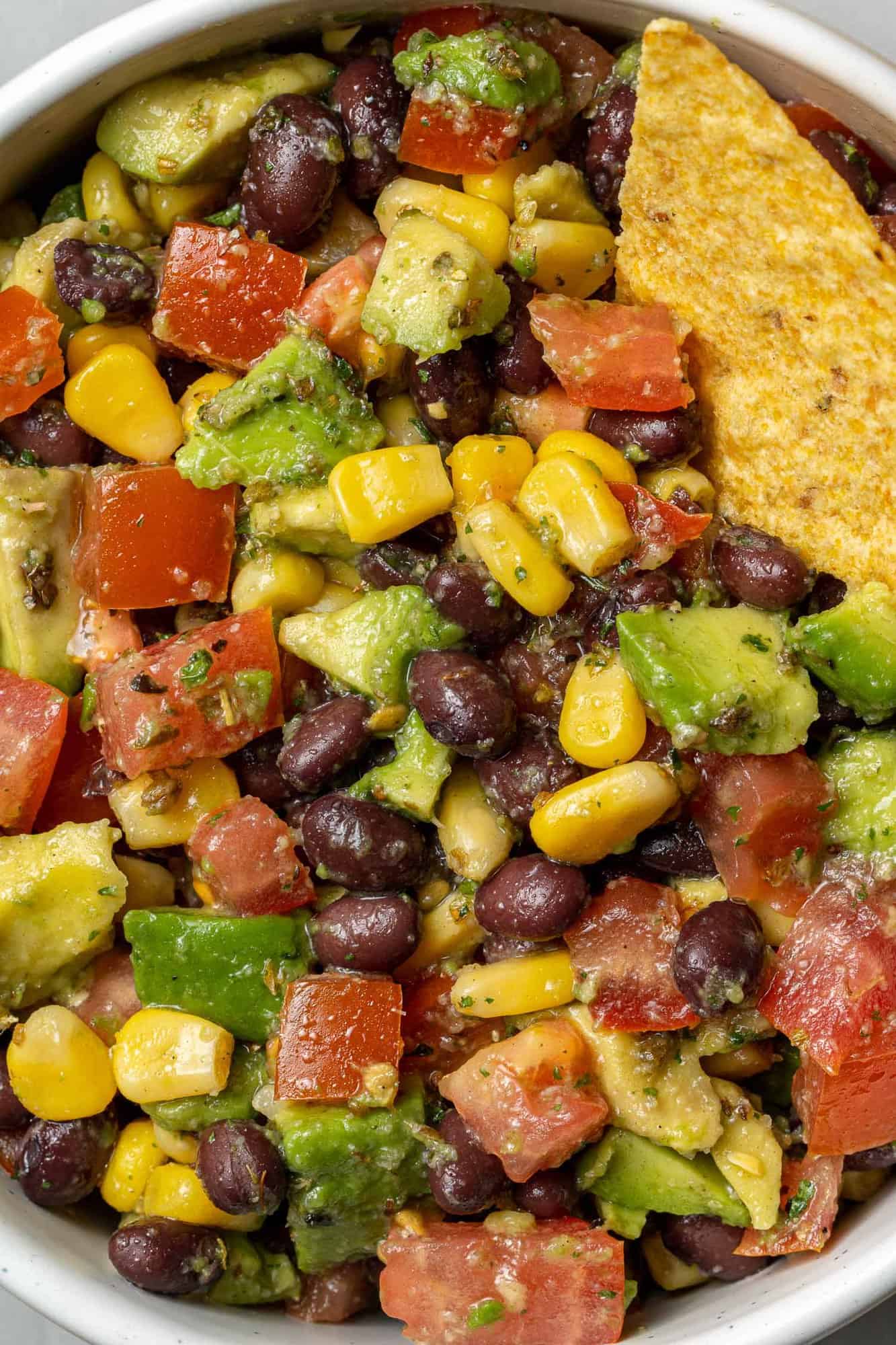 Close up view of salad with black beans, avocado, corn, tomatoes.