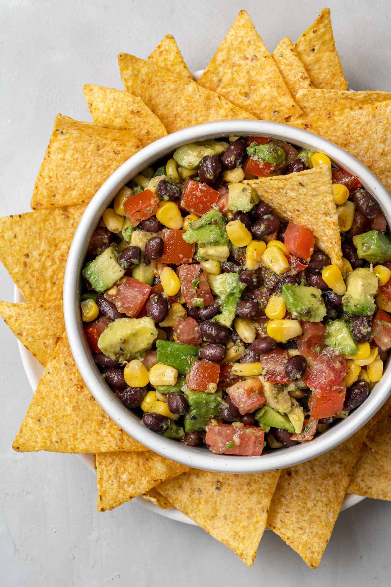 Overhead view of black bean, avocado, and corn salad with tortilla chips.