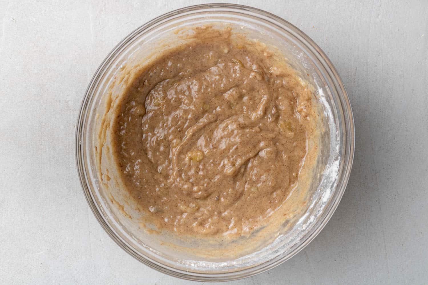 Donut batter in a clear glass bowl.