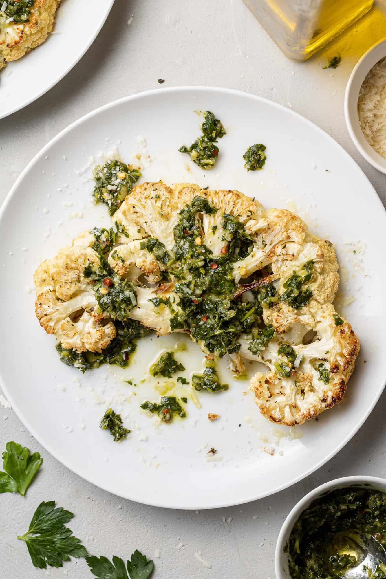 Thick slice of cauliflower, topped with green chimichurri sauce.