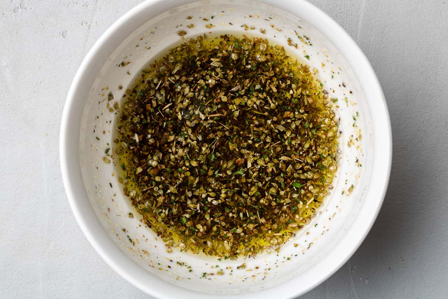 Olive oil and seasonings in a small white bowl.