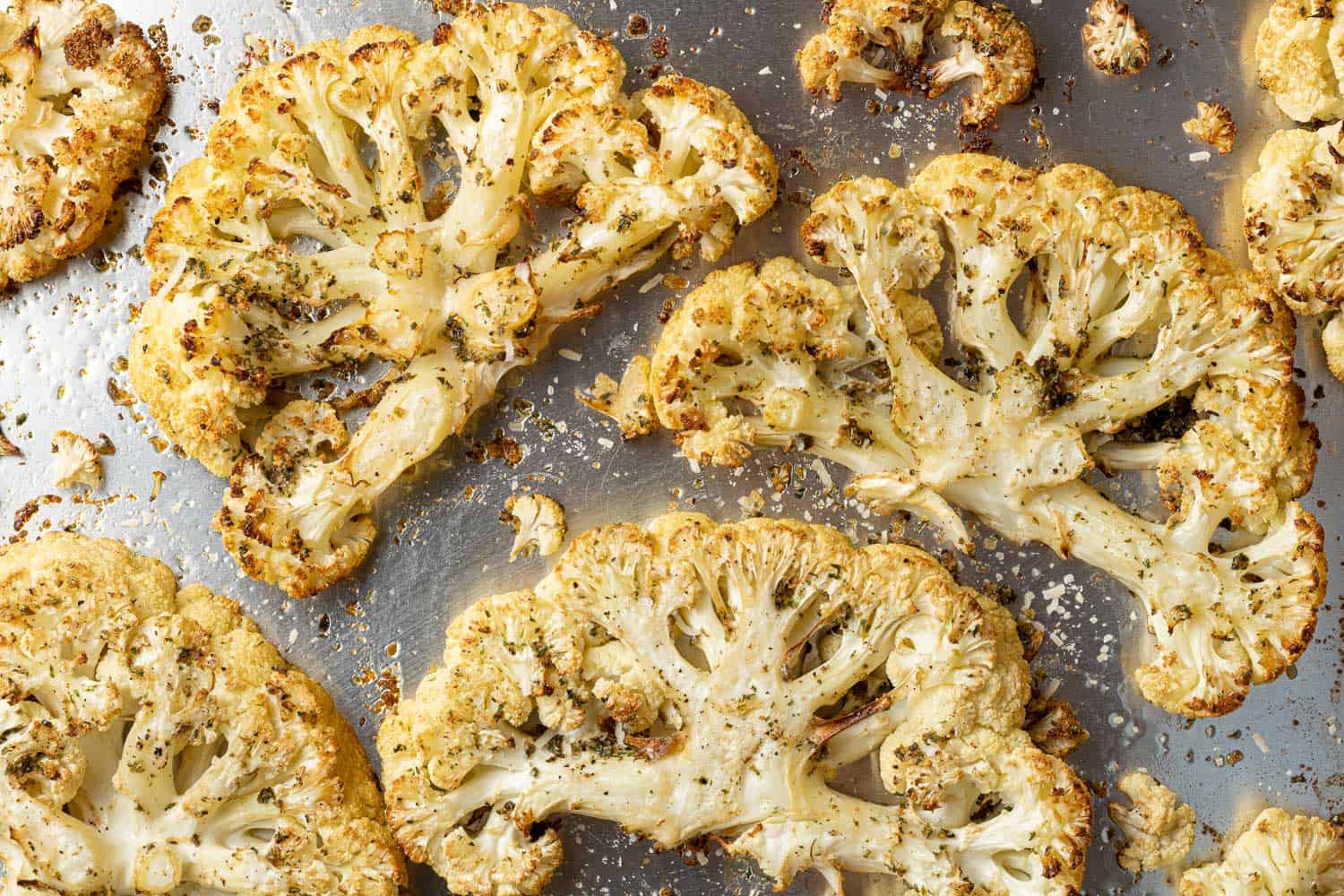 Roasted cauliflower slices on a silver sheet pan.