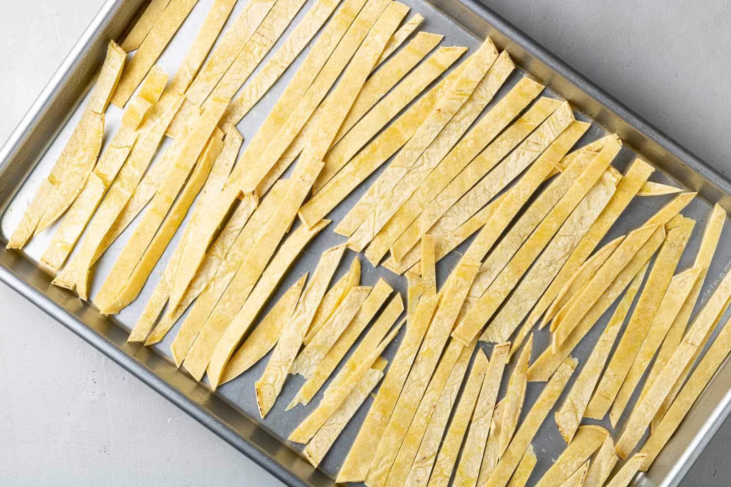 Tortilla strips on a baking sheet, not yet cooked.
