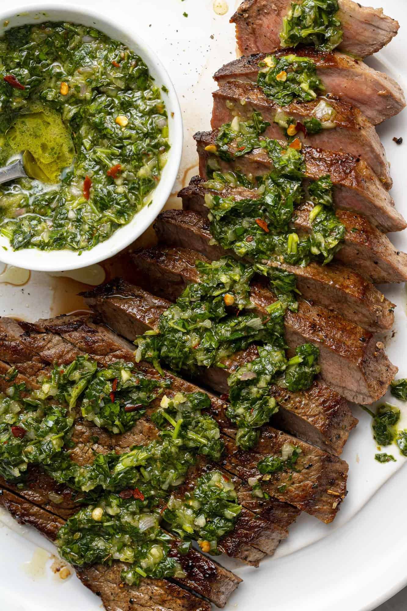 Close up of chimichurri on sliced steak.