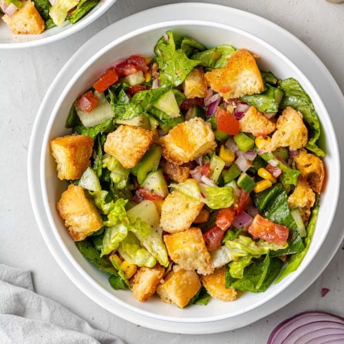 Overhead view of gazpacho salad with large croutons and corn.