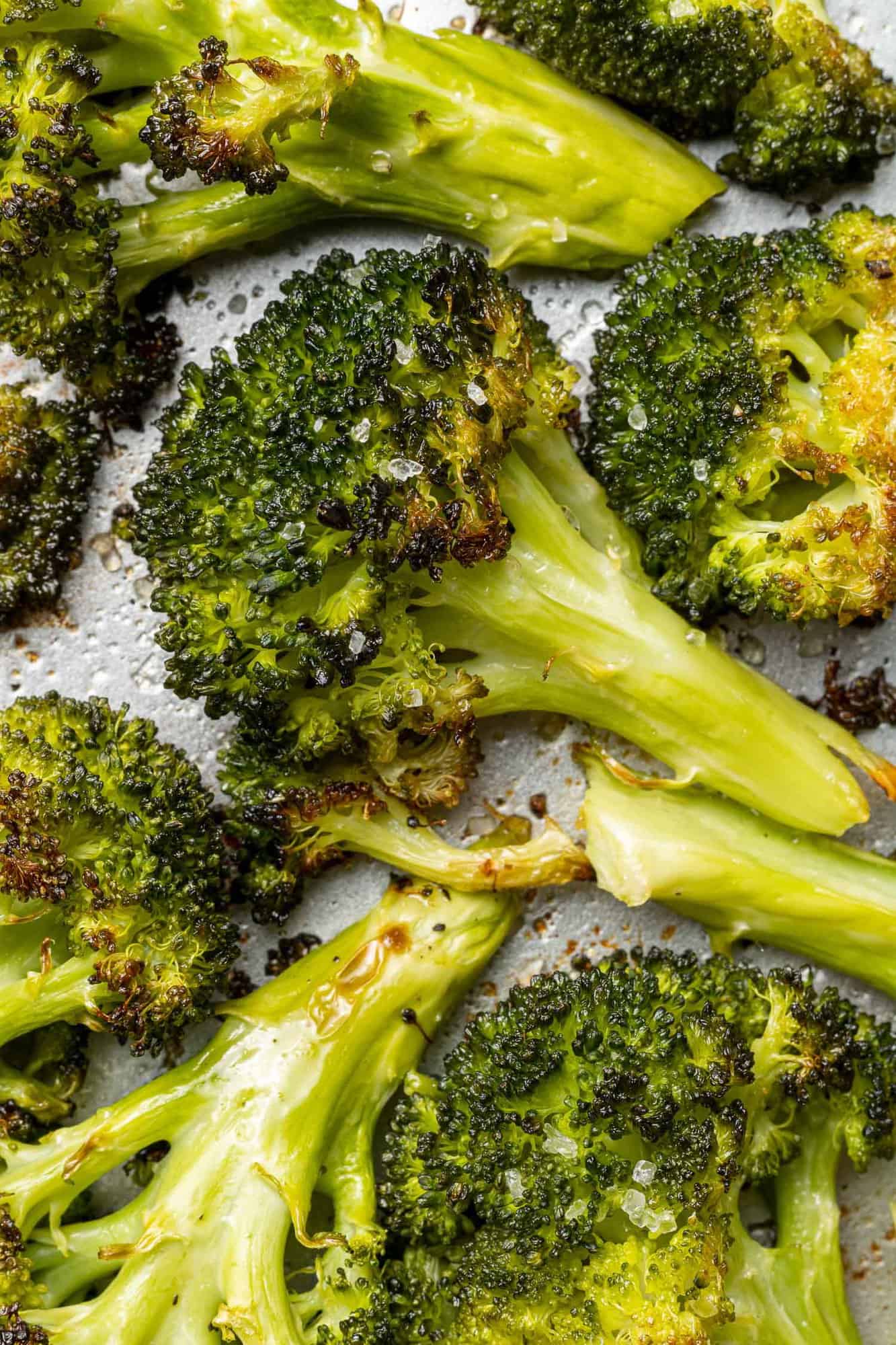 Close up view of crispy roasted broccoli floret, surrounded by others.