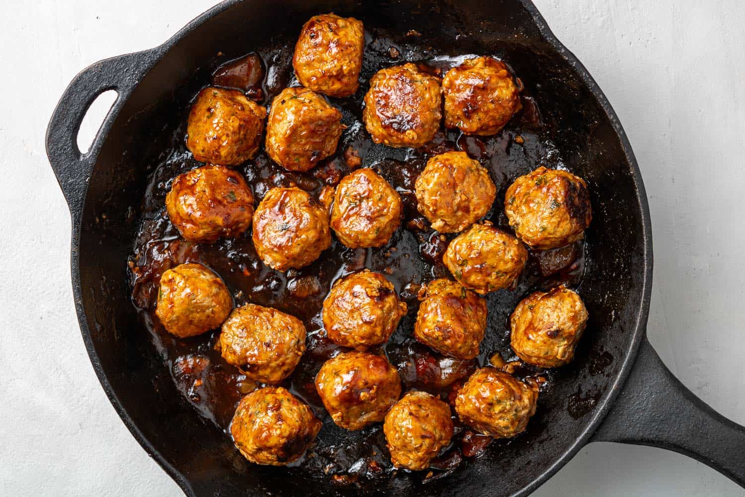 Glazed meatballs in a cast iron skillet.