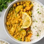 Vegetarian curry in a bowl with rice, topped with a lemon slice.