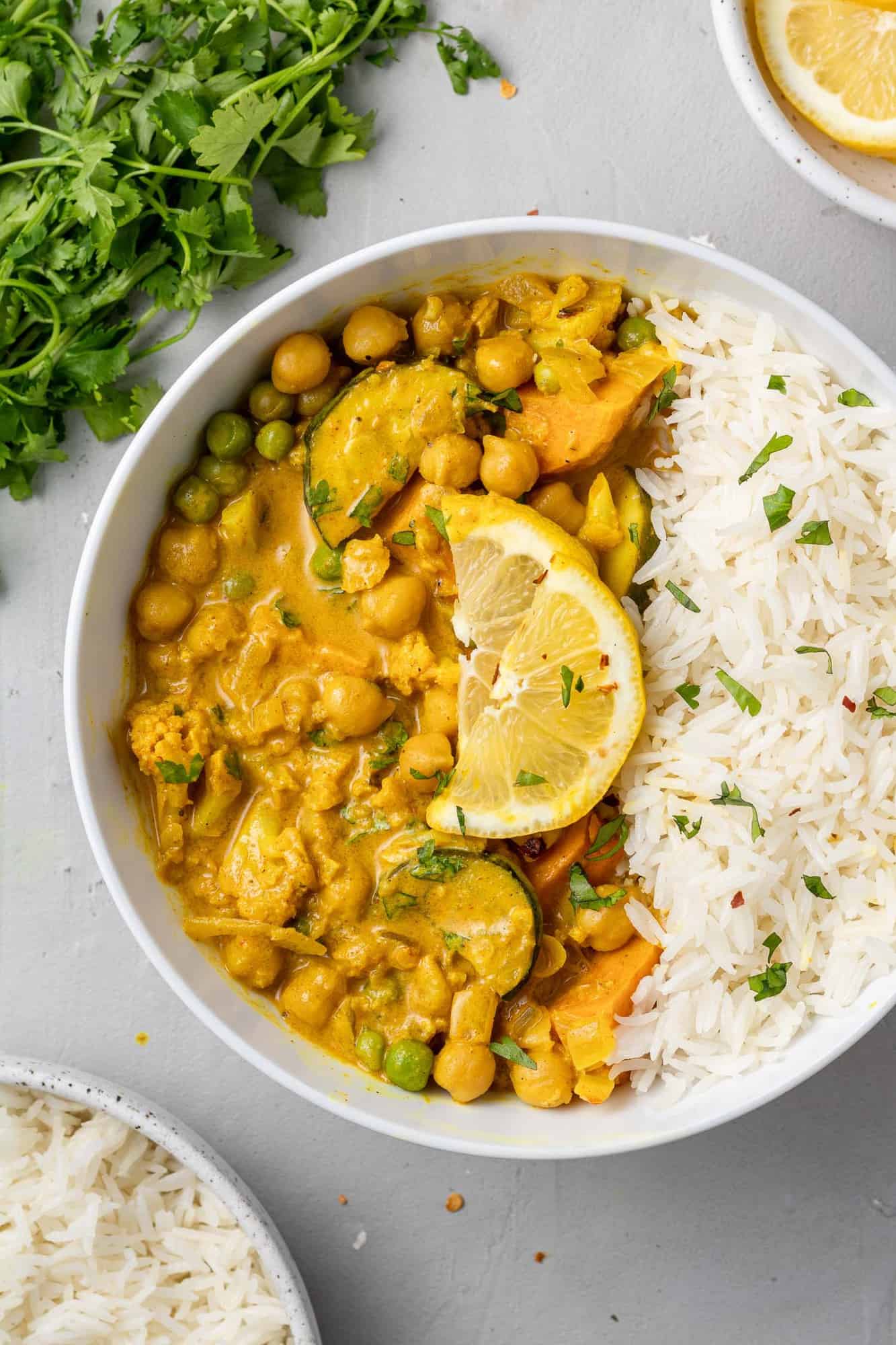 Vegetarian curry in a bowl with rice, topped with a lemon slice.