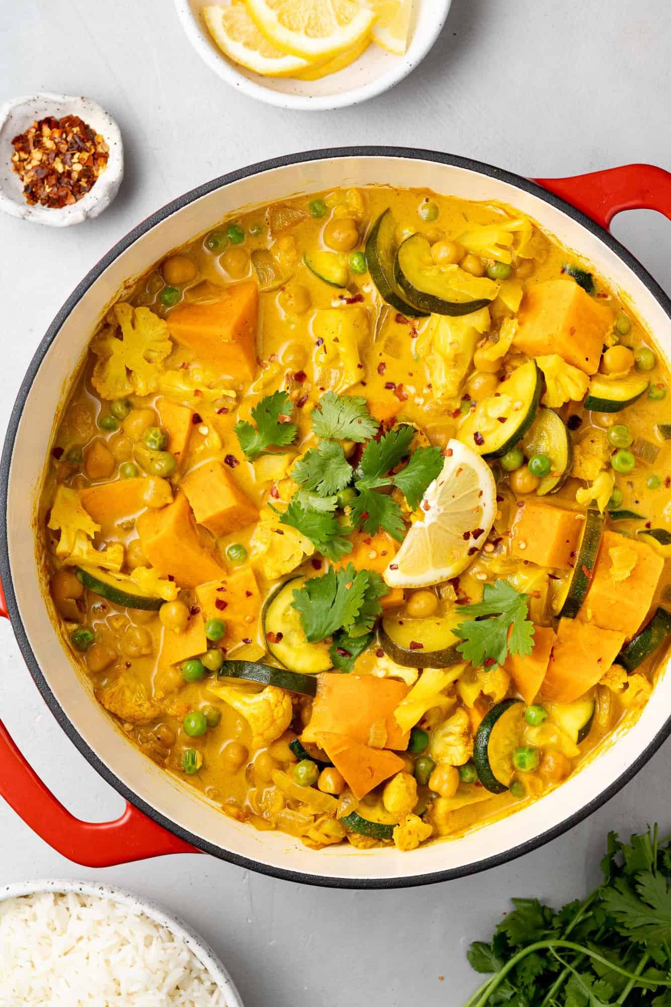 Overhead view of curry with sweet potatoes, chickpeas, and cauliflower in a large dutch oven.