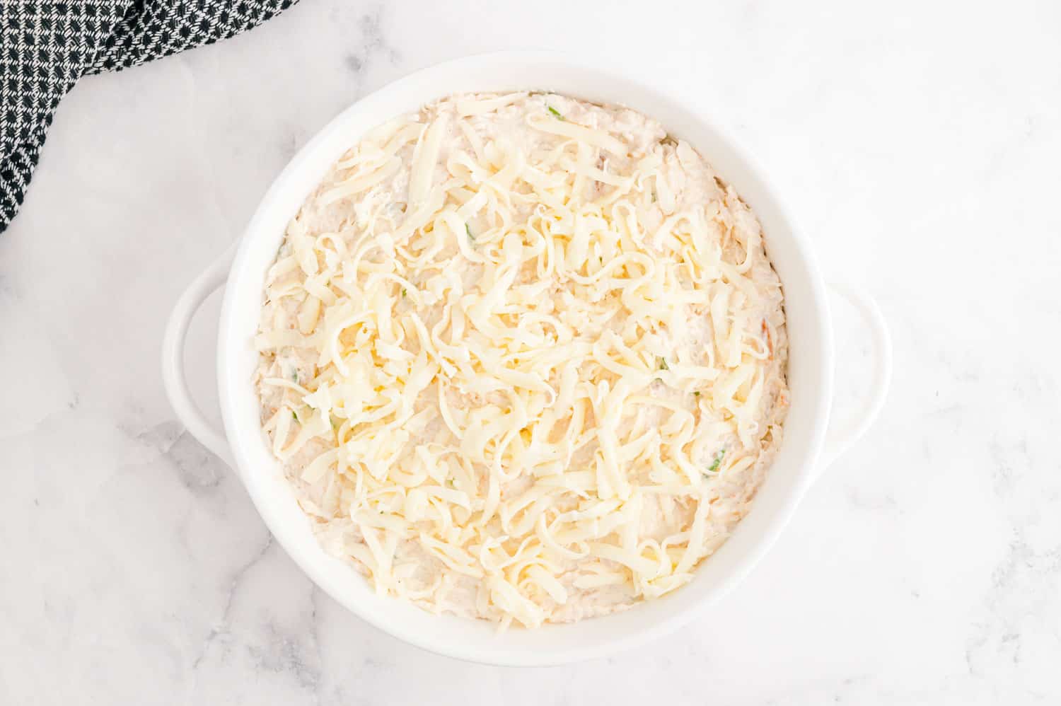 Unbaked dip in a round white baking dish.