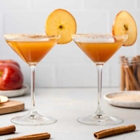 Two apple cider mocktails garnished with round apple slices.