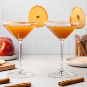 Two apple cider mocktails garnished with round apple slices.