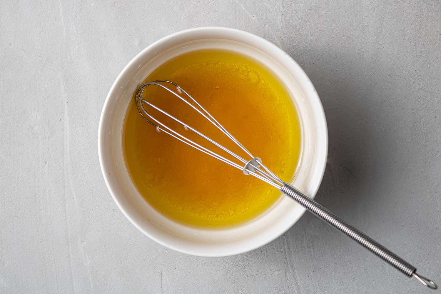 Dressing in a small white bowl with a little whisk.