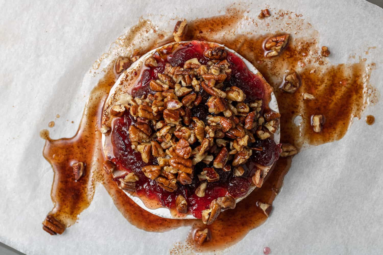 Pecans and cranberries on top of brie, not yet baked.