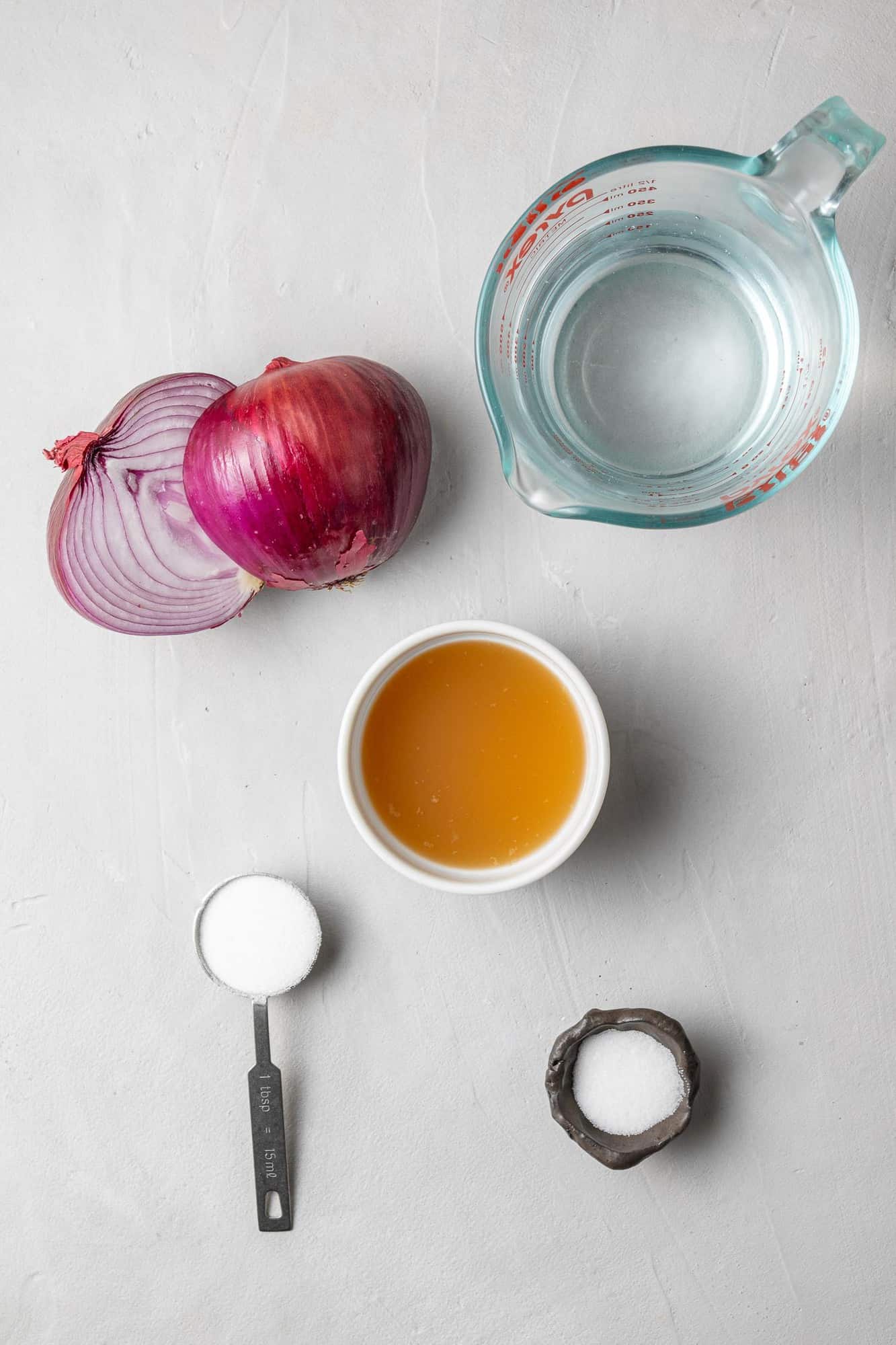 Overhead view of ingredients: red onion, vinegar, water, salt, sugar.