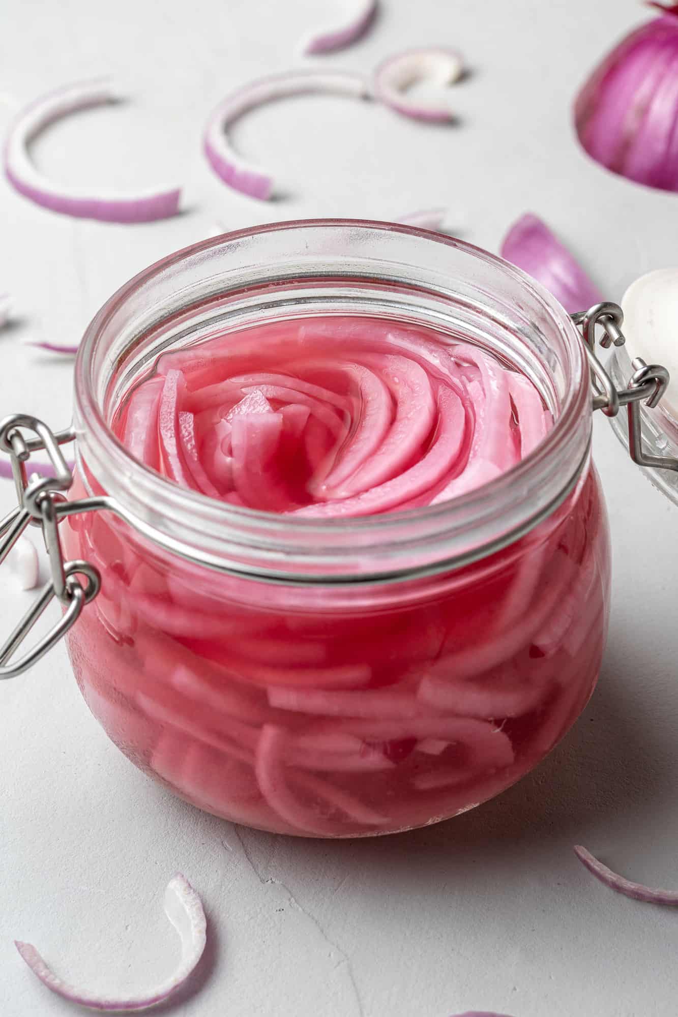 Pickled red onions in a small clear glass jar.
