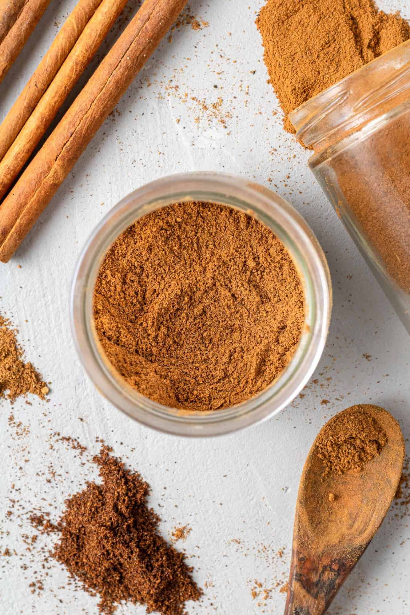 Overhead view of homemade pumpkin spice in a jar, with ingredients surrounding it.