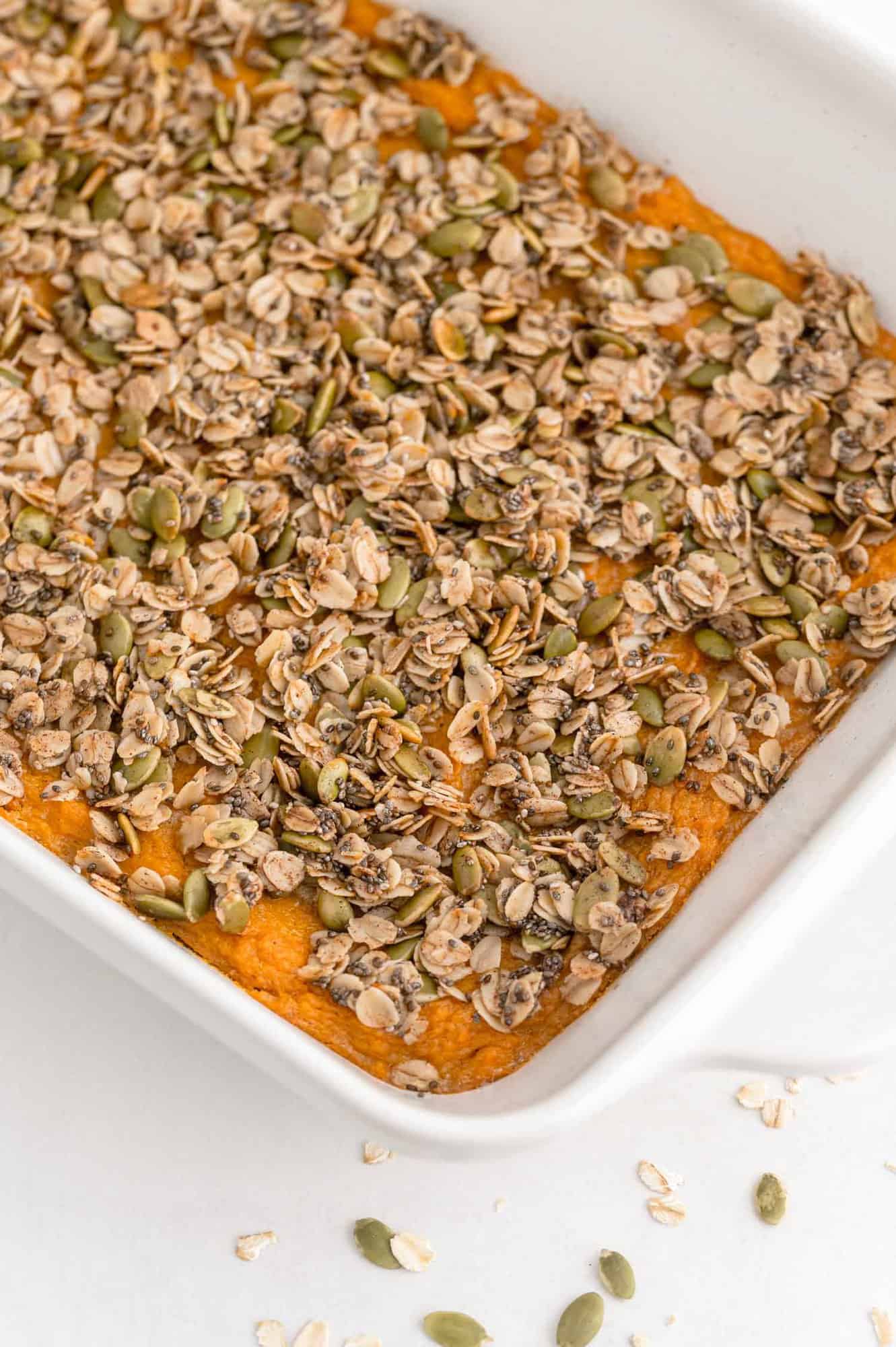 Sweet potato casserole with an oat topping in a white casserole dish.