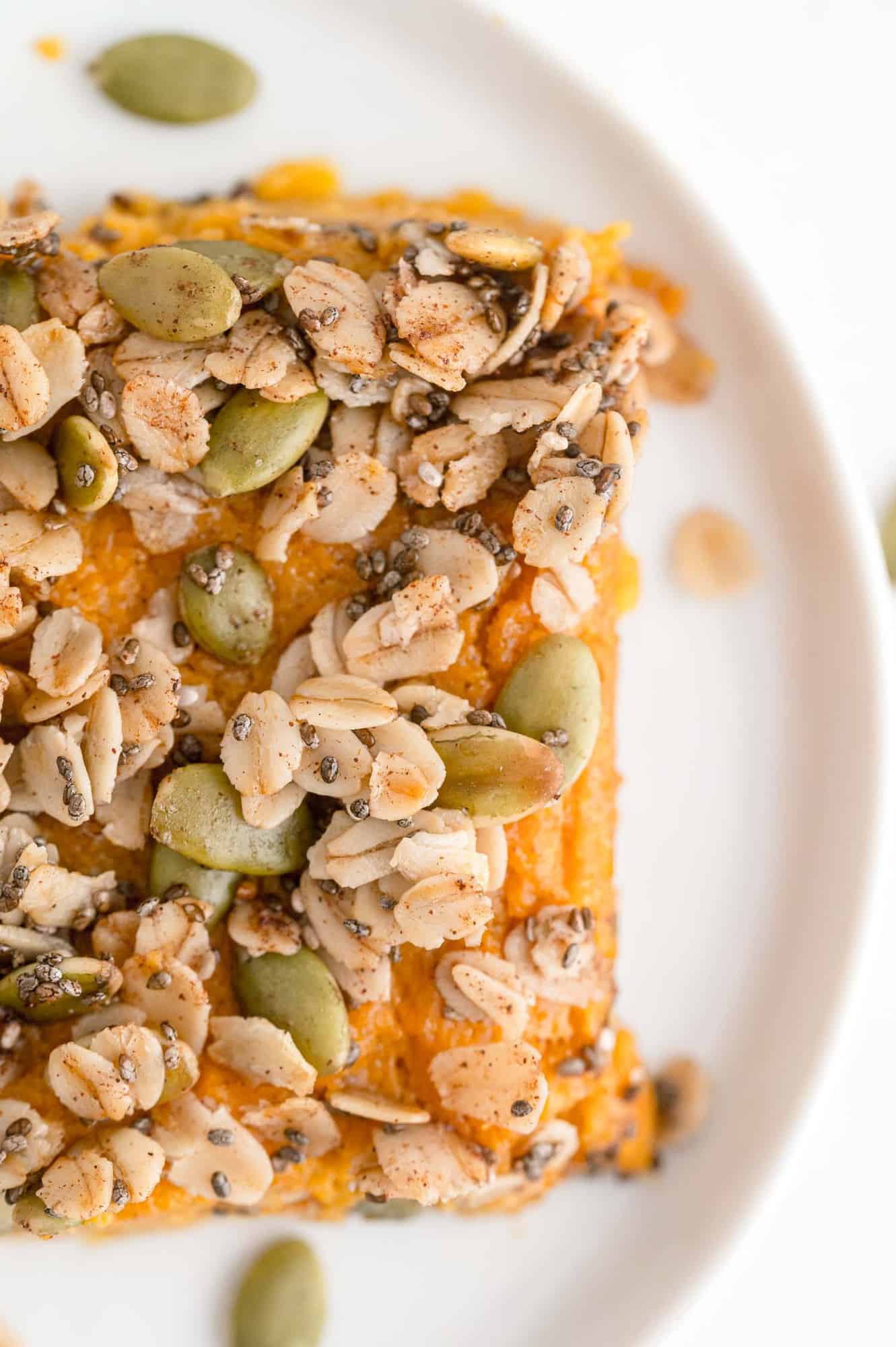 Overhead view of a square of sweet potato casserole on a round white plate.