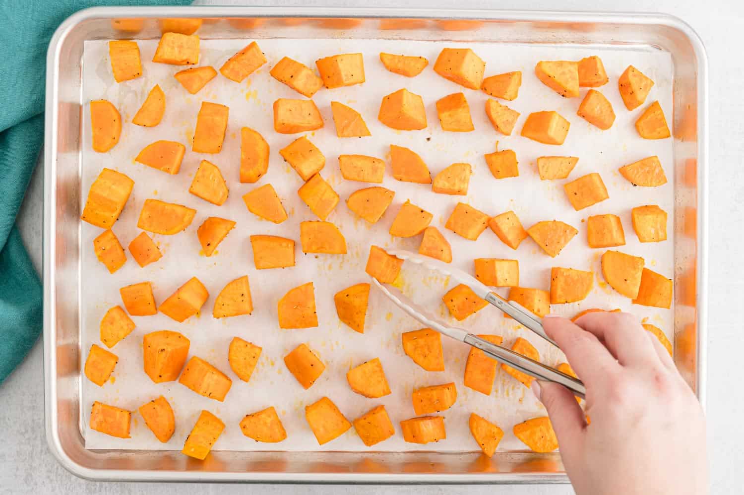 Tongs flipping sweet potatoes.