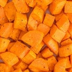 Close up view of cubed roasted sweet potatoes seasoned with salt and pepper.