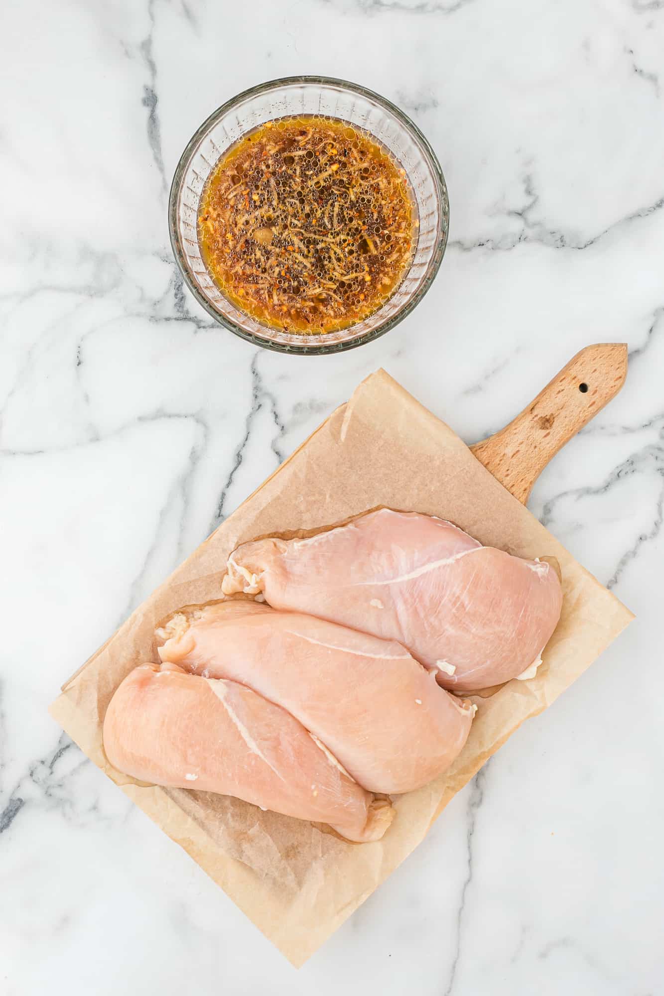 Raw chicken, and a small bowl of marinade.