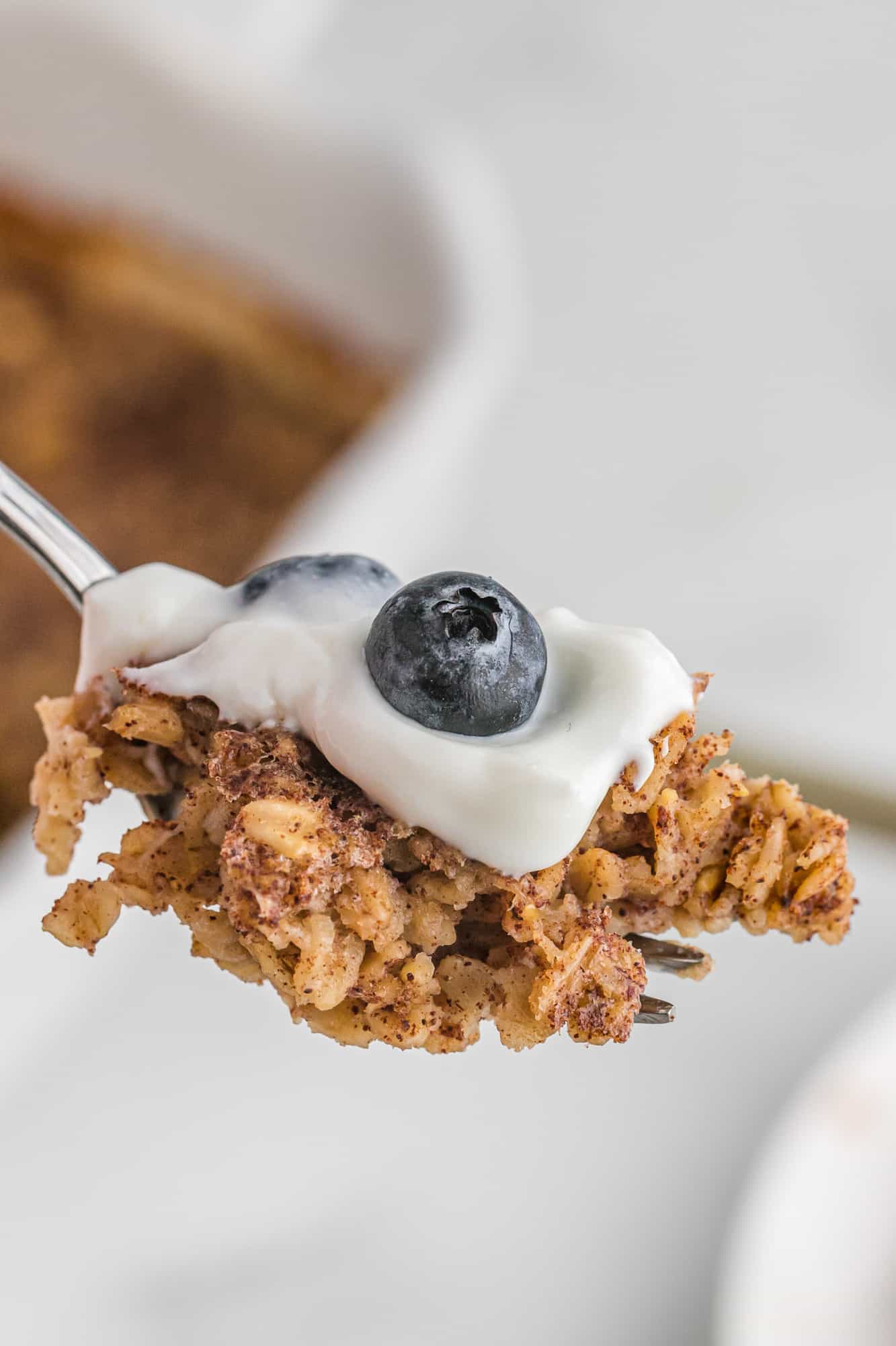 Baked oatmeal on a fork with yogurt and blueberries.