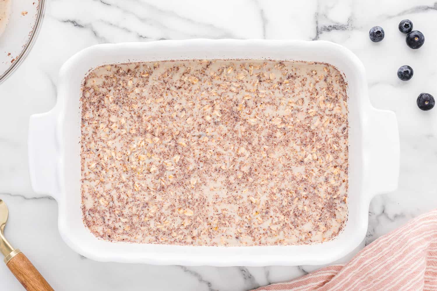 Unbaked oatmeal in a white casserole dish.