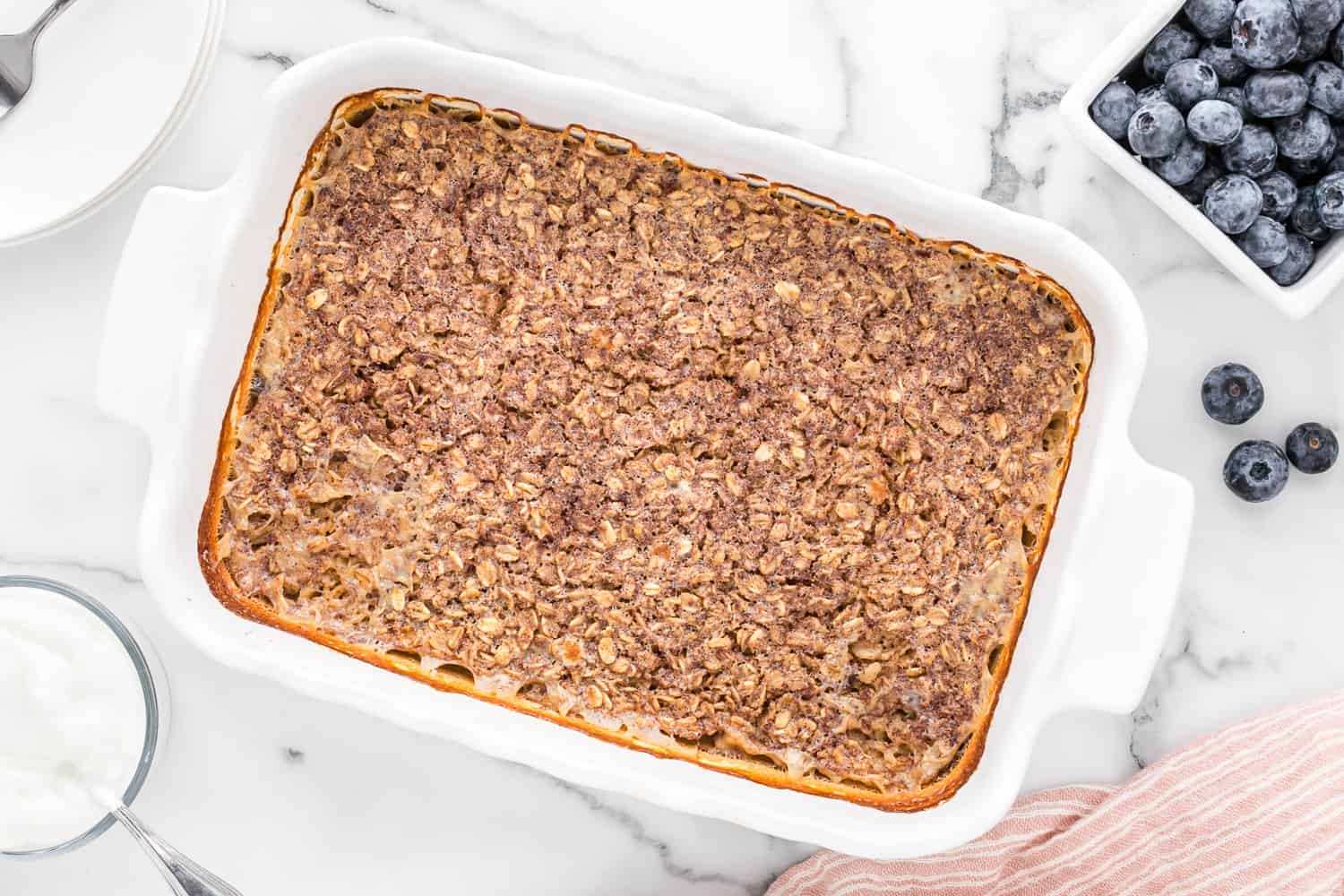 Baked oatmeal, uncut, in a white casserole dish.