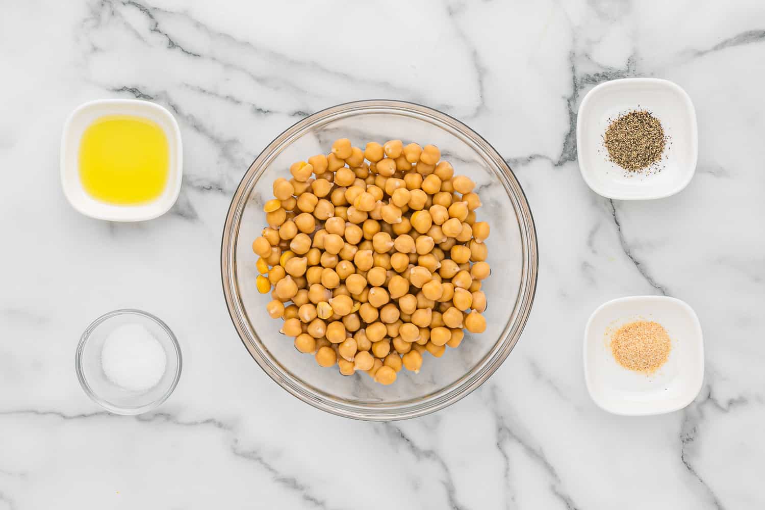 Overhead view of ingredients needed including chickpeas, olive oil, salt, and pepper.