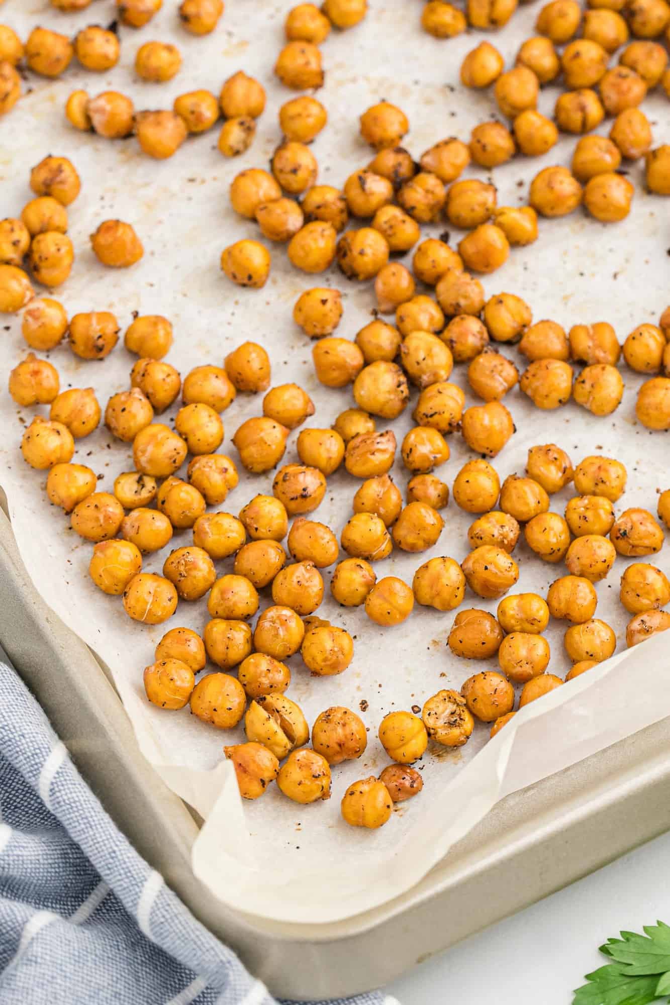 Chickpeas, roasted, on a sheet pan lined with parchment.