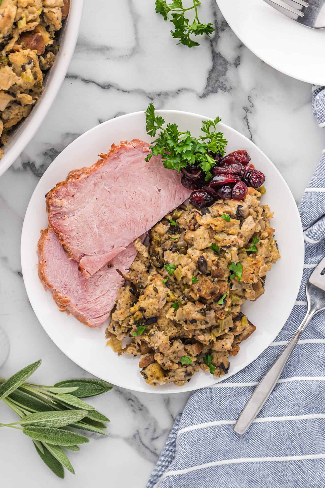 Dressing on a white plate with ham and cranberries.
