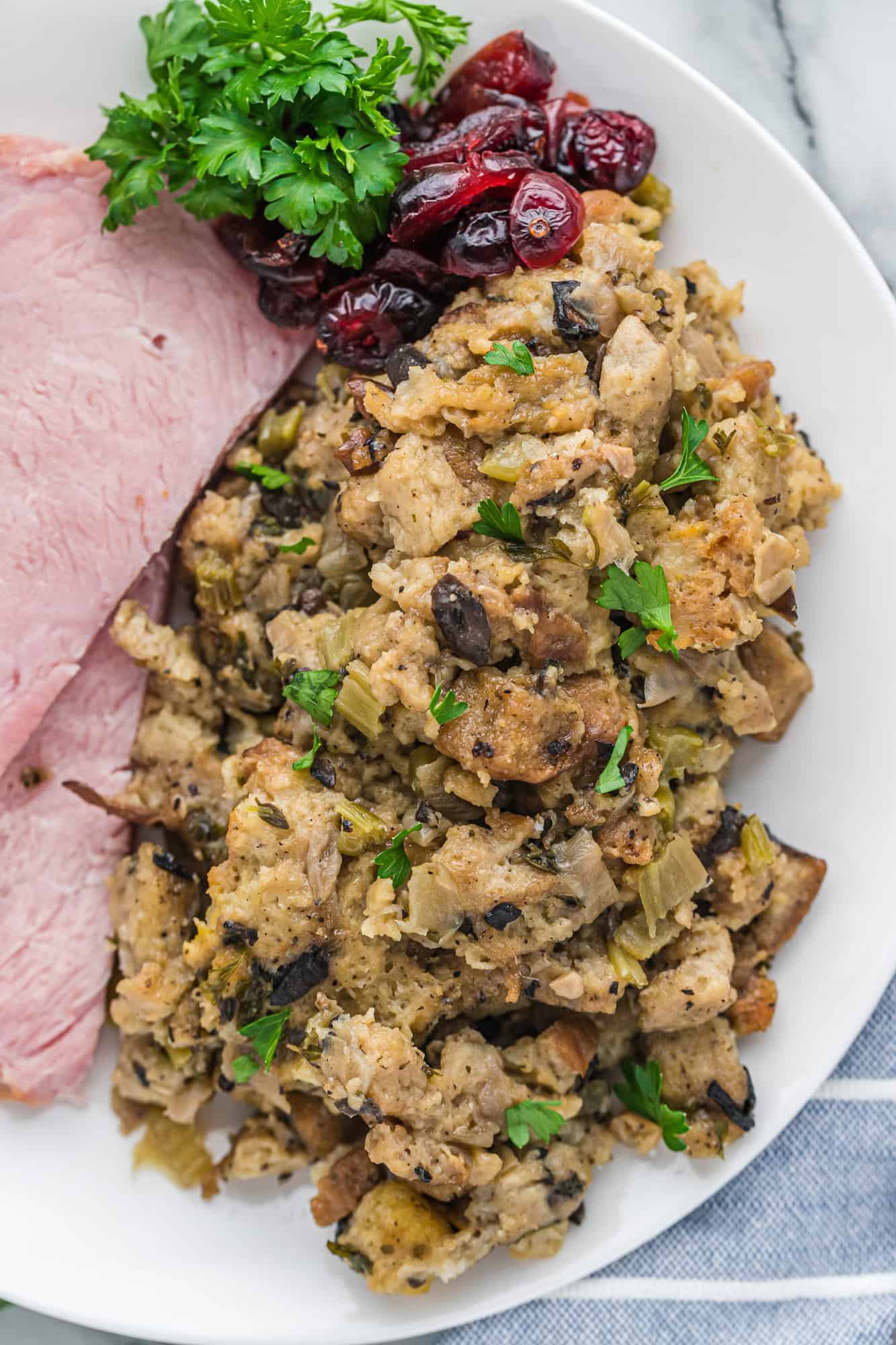 Close up of stuffing on a plate with ham and cranberries.