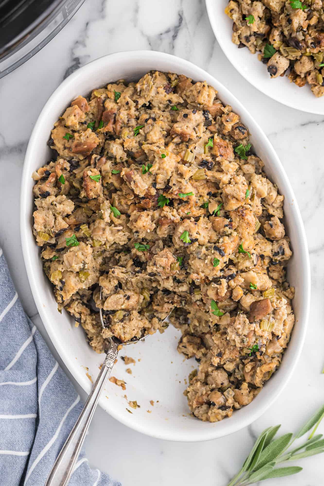 Stuffing in a large white serving dish with a scoop removed.